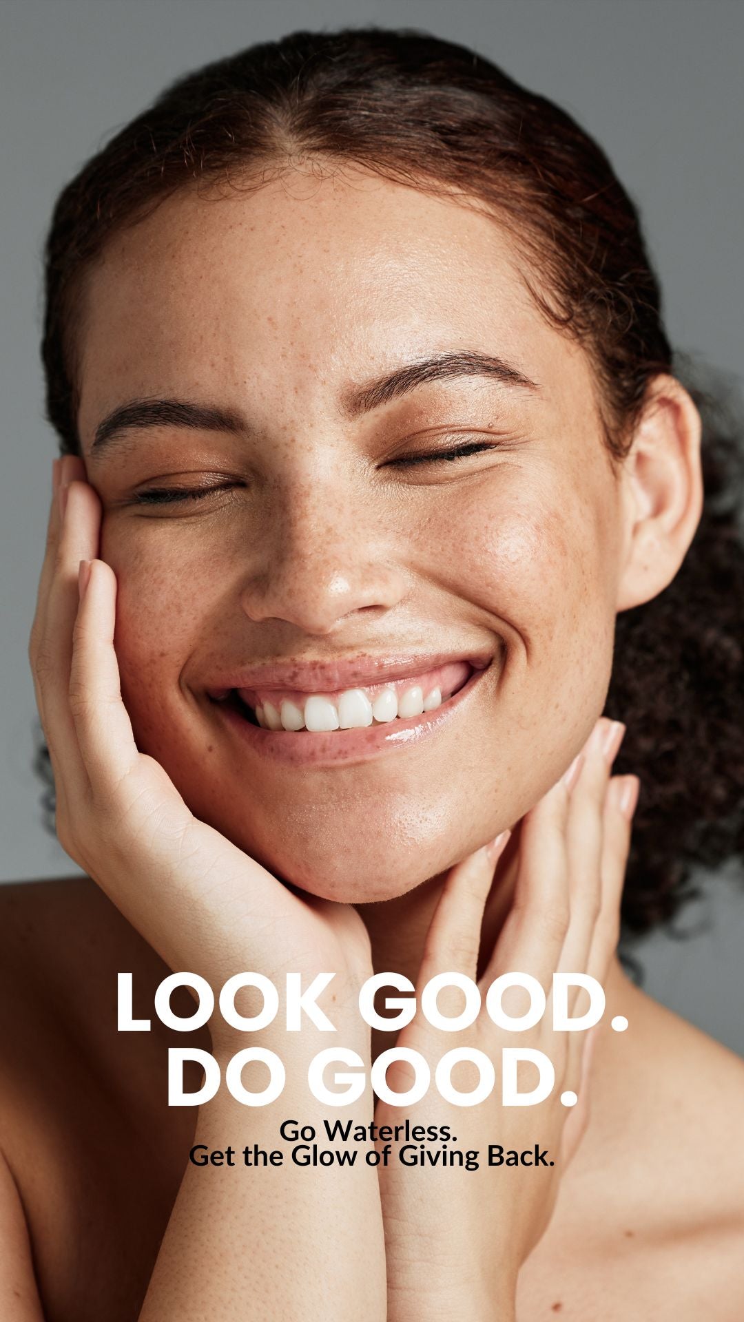 Smiling woman touching her face against gray background with overlaid text 'LOOK GOOD. DO GOOD.'