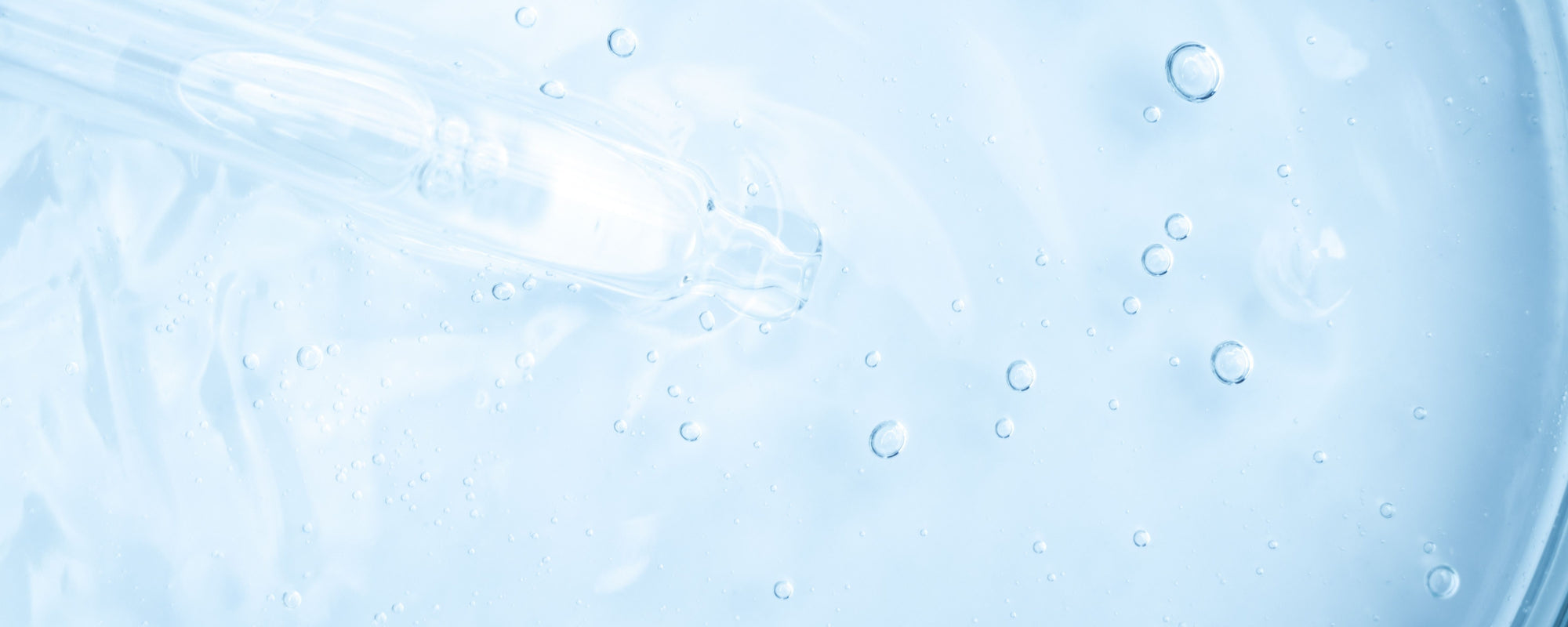 Clear serum with glass dropper and suspended bubbles on pale blue background