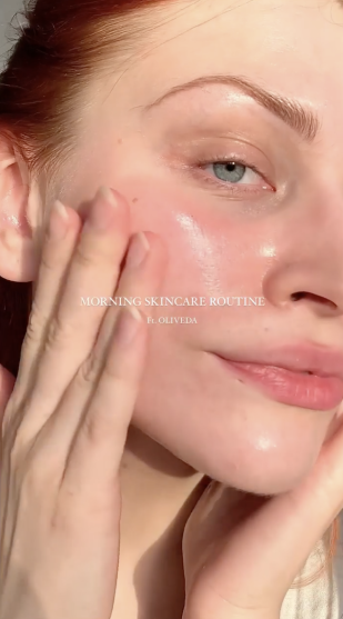 Close-up of a woman applying moisturizer, dewy skin; overlay text: MORNING SKINCARE ROUTINE Ft. OLIVEIDA