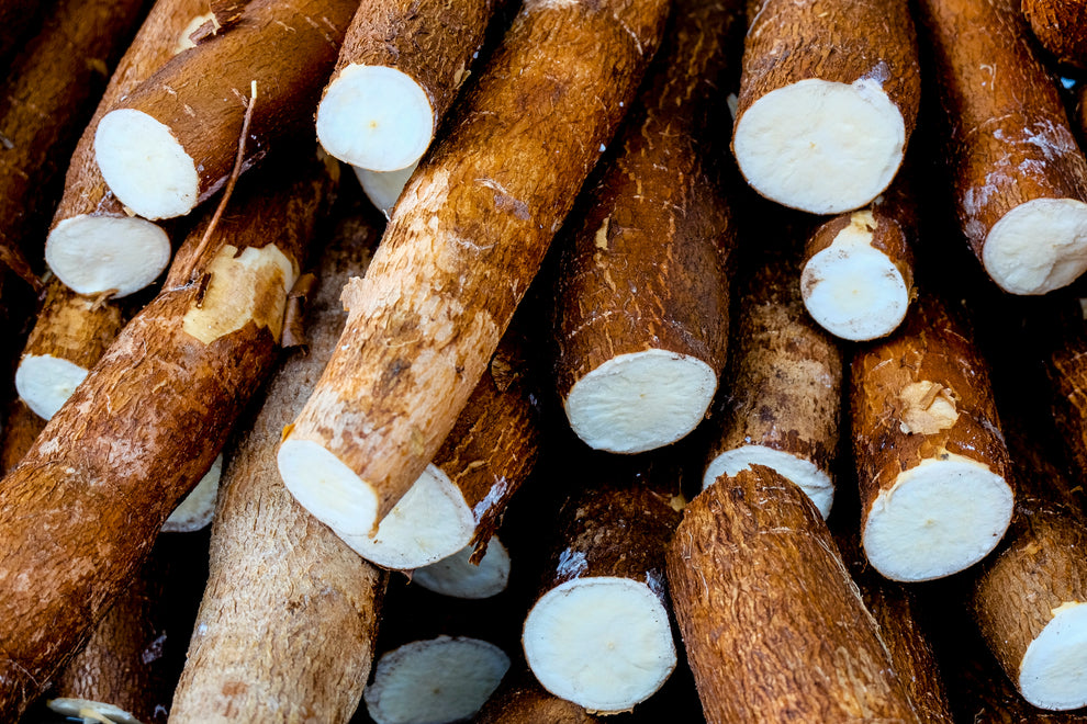 Stack of cassava (yuca) roots, some cut to show white starchy flesh