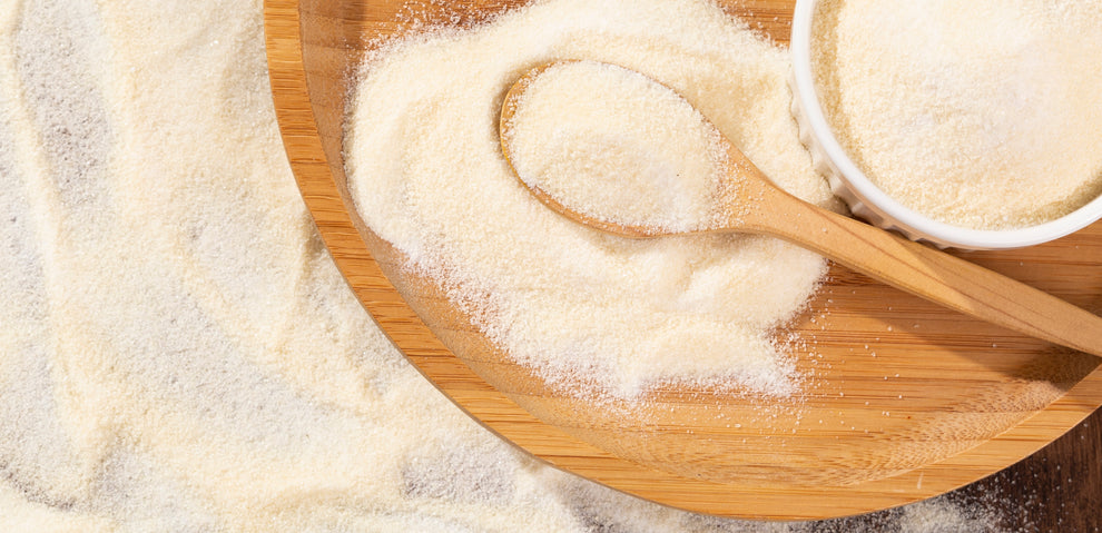 Semolina granules on a wooden platter with a wooden spoon and a white ramekin