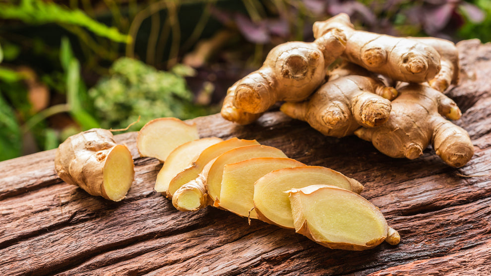 Fresh ginger root with several thin slices arranged on a wooden board