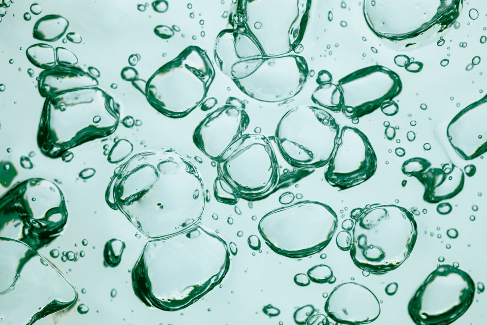 Green translucent liquid bubbles suspended in water, close-up abstract texture