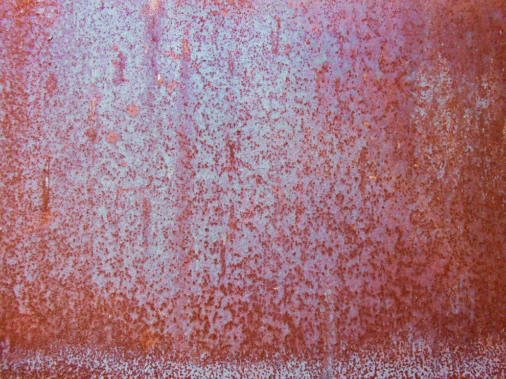 Rusted, speckled metal surface with reddish-brown corrosion over pale blue-gray paint, close-up texture