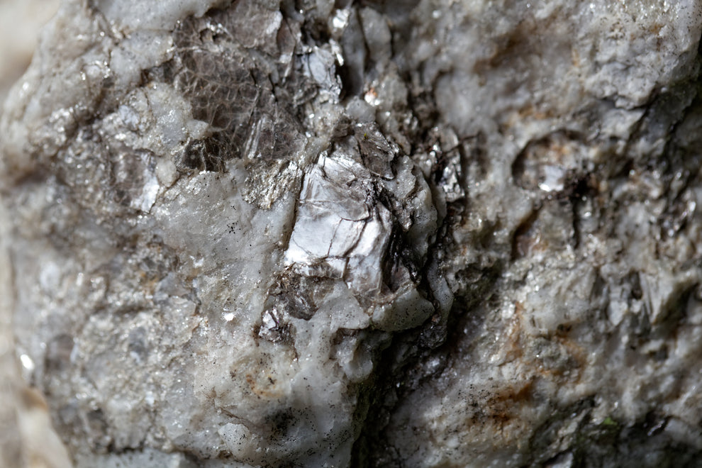 Macro view of mica-rich rock with silver flaky minerals embedded in white quartz