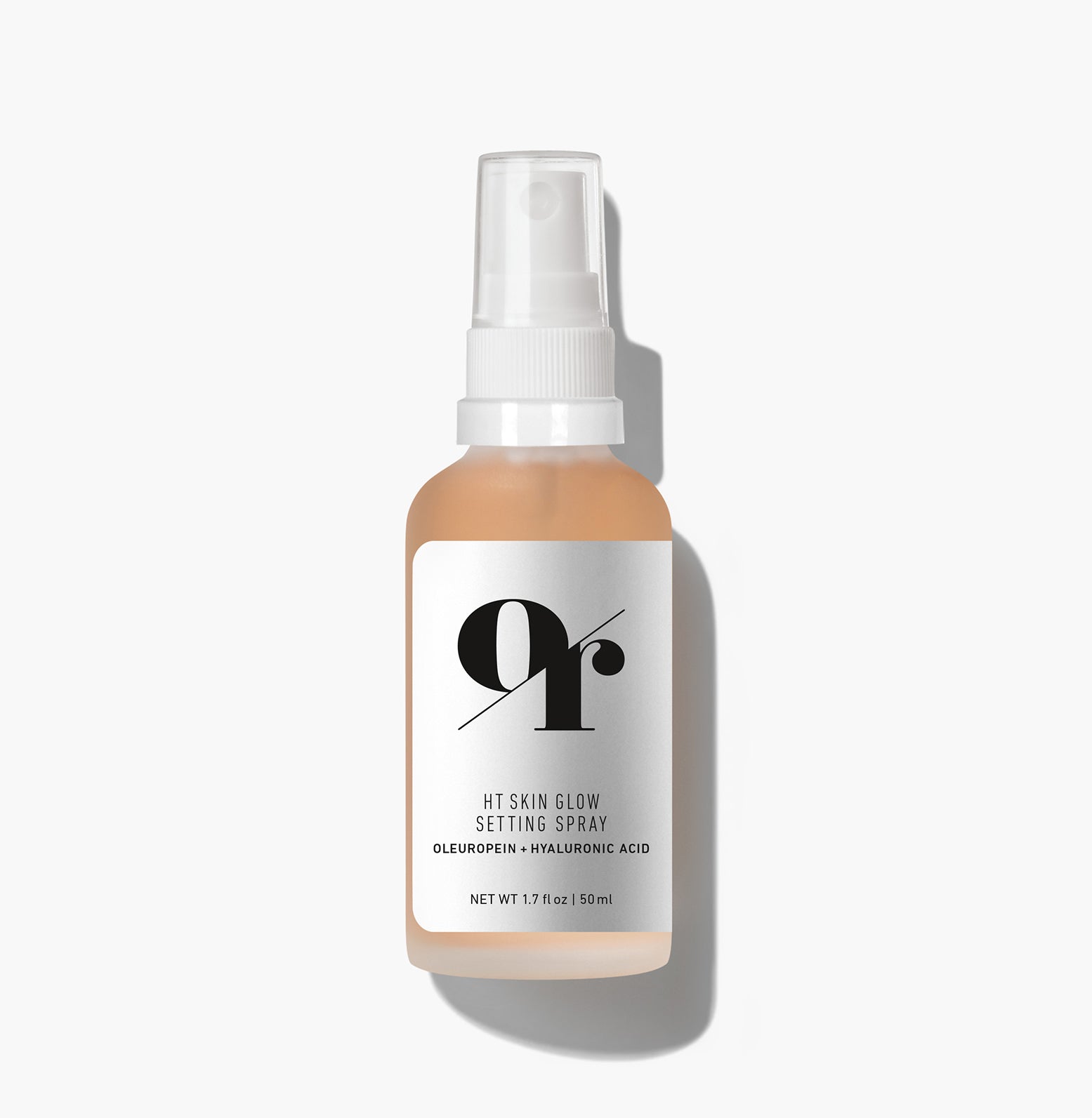 Front view of HT Skin Glow Setting Spray bottle showing frosted glass, peach-tinted liquid, white spray cap on white background