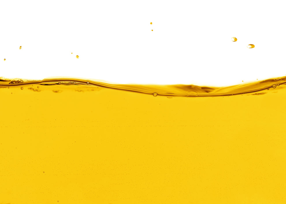 Golden oil wave with small droplets against a white background
