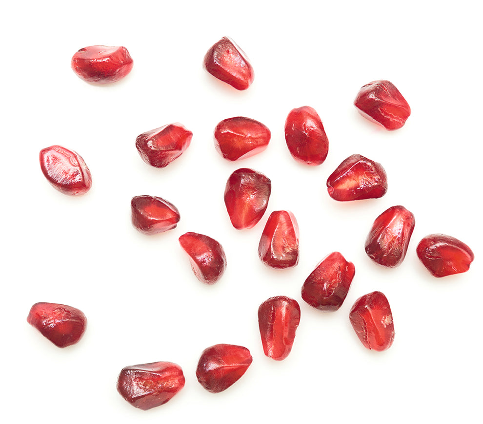Pomegranate arils scattered on a white background