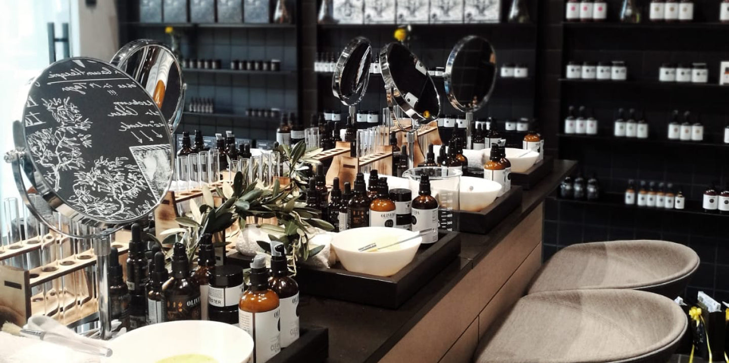 Skincare counter with round mirrors, wooden test-tube racks, amber dropper bottles, white bowls and two gray stools